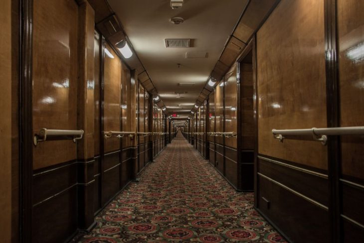 Dimly lit hallway inside the Queen Mary, where spectral figures are rumored to roam.